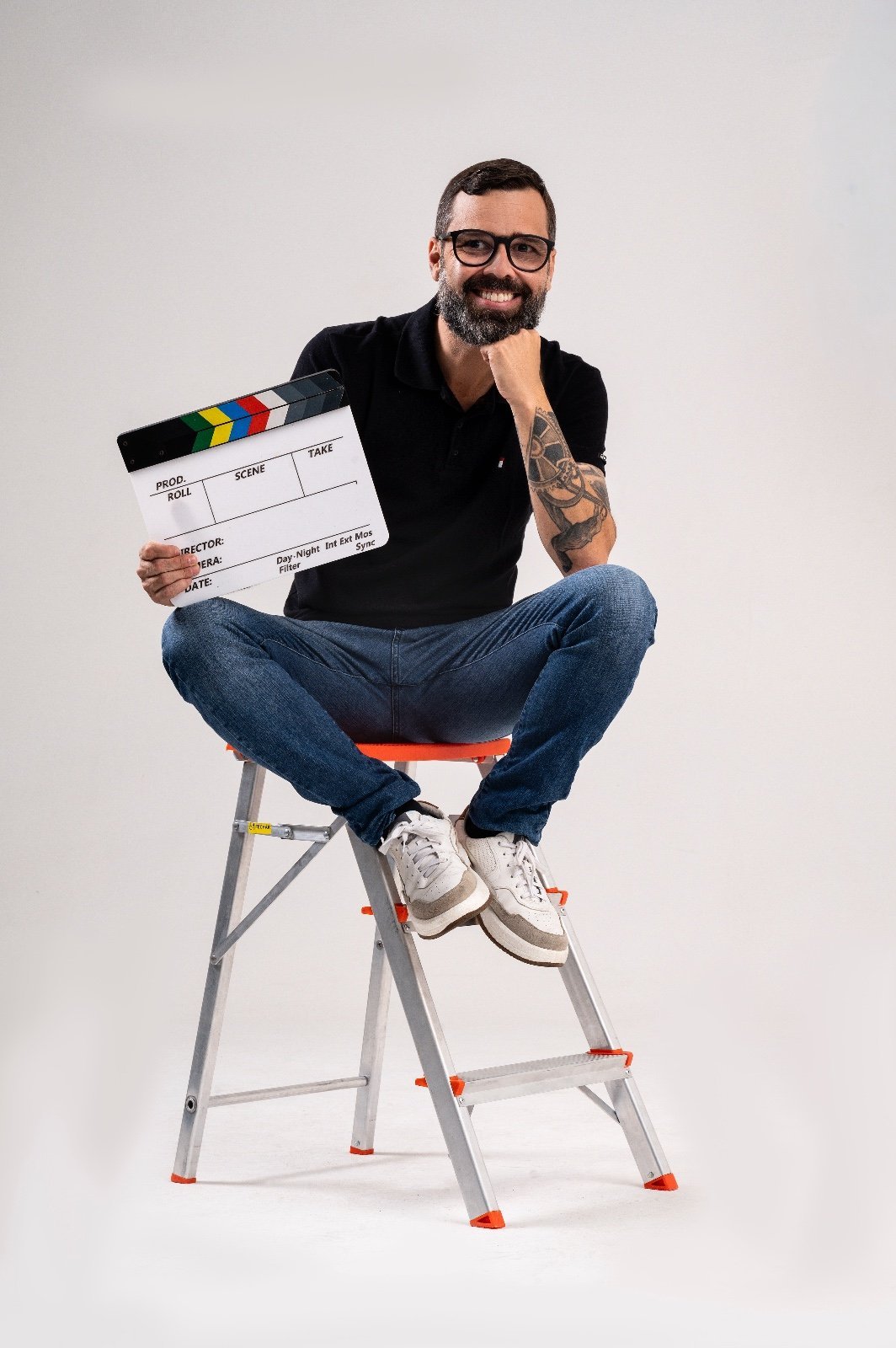 Filipe sentado em escada segurando clapperboard de filme